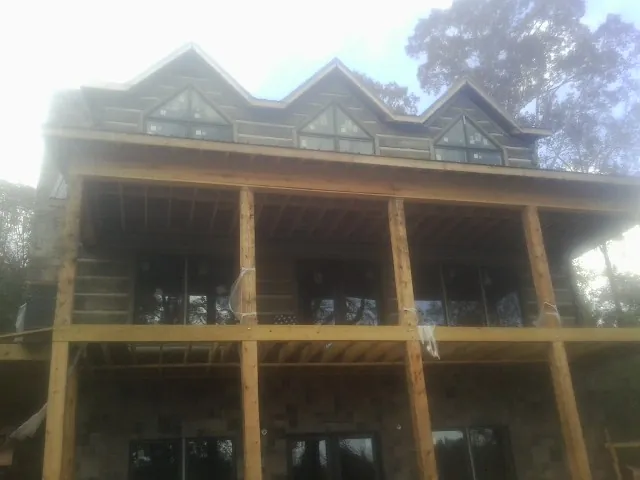Dormers and porch framing on a large log home under construction — Roof Coating work by our crew in Sandy Hook