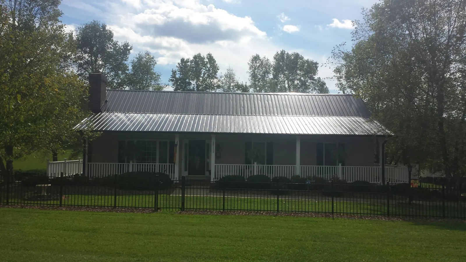 Gray metal roof on a brick ranch with a full width front porch — Gutter Guard Installation work by our crew in Sandy Hook