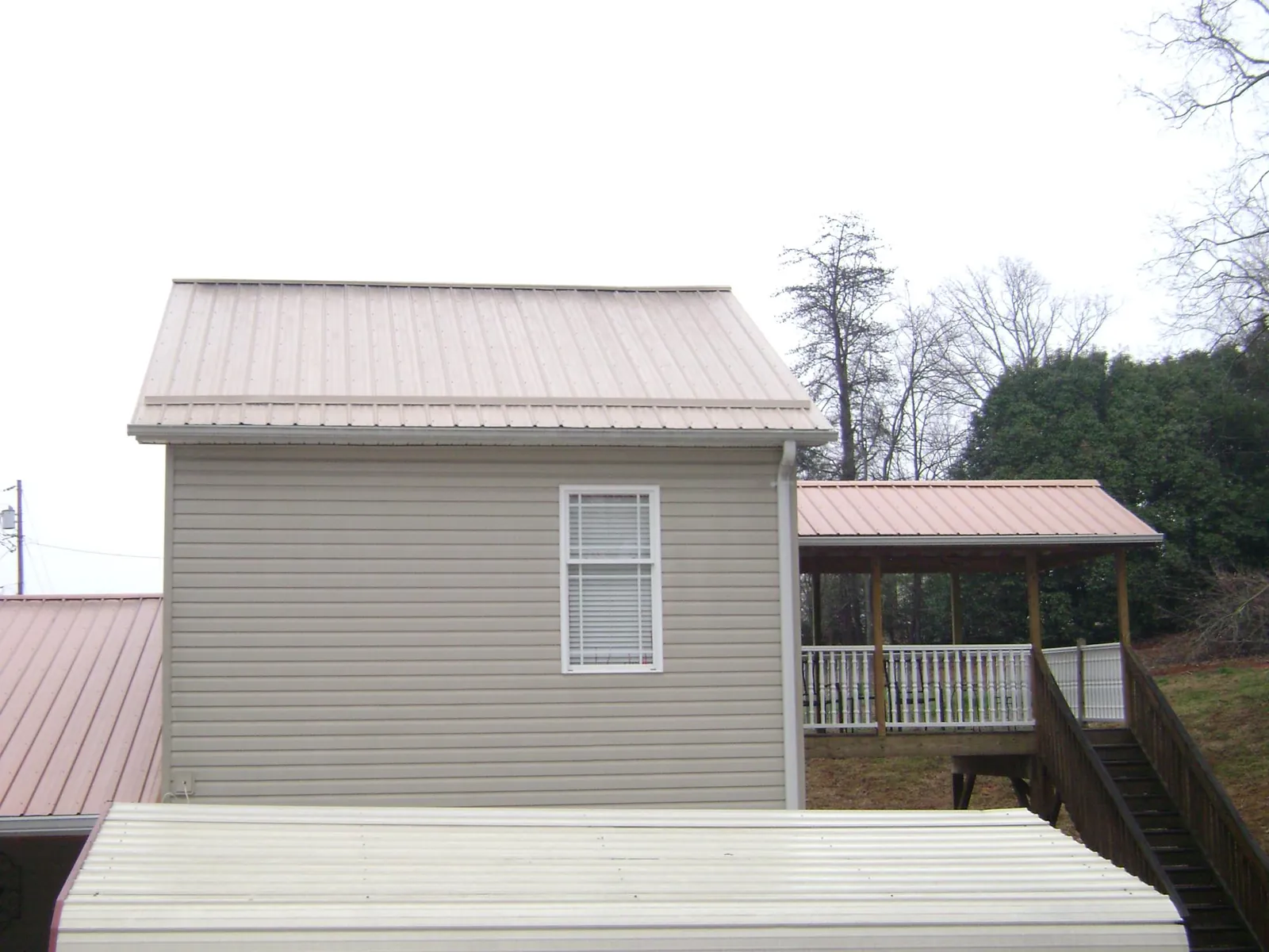 Tan metal roofs on a two story addition and attached porch, from a Roof Replacement job in Sandy Hook